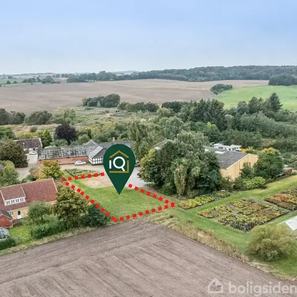 Grønt areal markeret med rød stiplet linje står i midten, omkranset af beboelseshuse og marker i landligt område. Ikon med teksten "iQ" er placeret centralt. Tekst: "Vejledende".