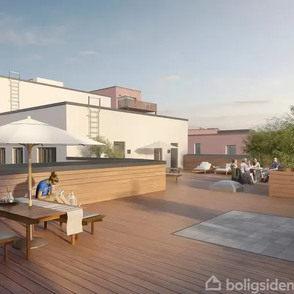 En tagterrasse med et træbord under en parasol, hvor en person sidder. Omkranset af hvide og rosa bygninger ses et opholdsområde med grill og folk i baggrunden.