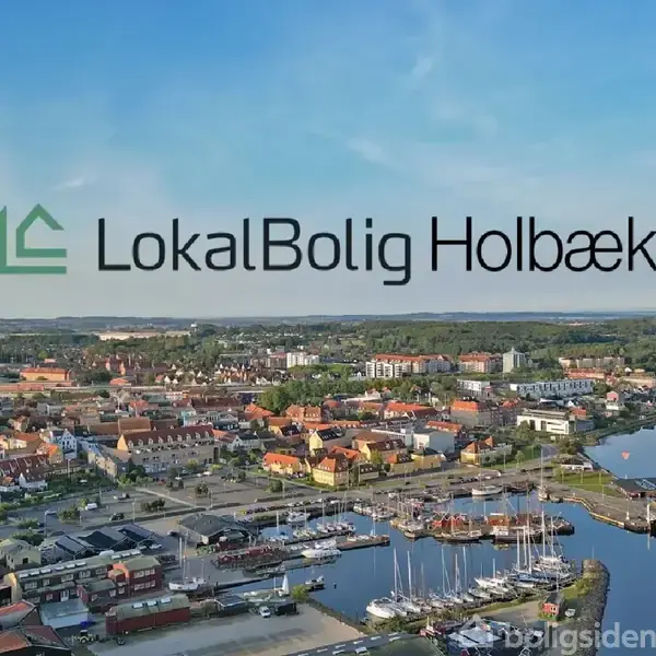 Kystby med havn og både i forgrunden, mange huse spredt ud over landskabet. Tekst: "LokalBolig Holbæk".