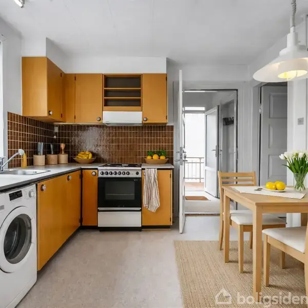Køkken med træskabe og brun mosaikflisevæg, indeholder komfur, vaskemaskine og bord med to stole. Store vinduer bringer naturligt lys ind, og grønne planter pynter rummet.