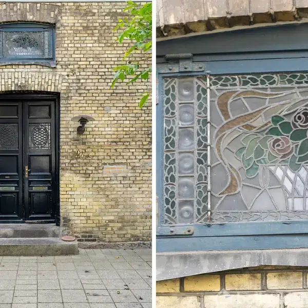 Sort dobbeltdør med glaspartier står i en facade af gule mursten, flankeret af væglamper. Ved siden af er et nærbillede af et kunstglasvindue med blomster- og rosemotiv.