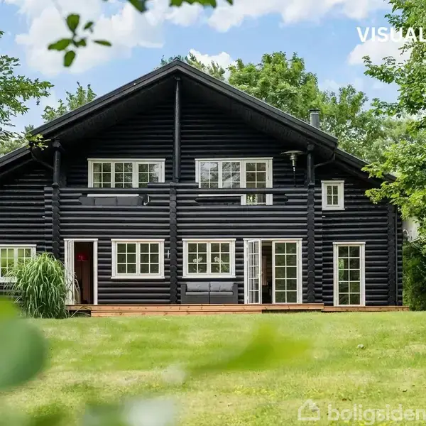 Sort bjælkehus står stille midt i en grøn have omringet af træer. Øverst til højre er skrevet "VISUALISERING".