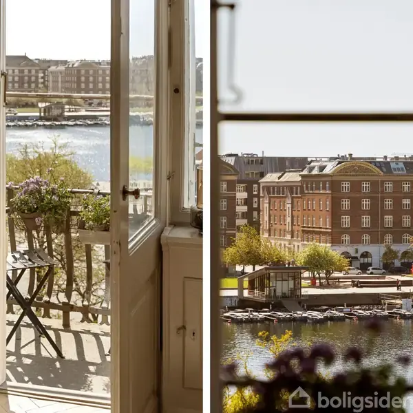 Døre åbner mod en altan med et cafébord og planter. Udsigt over flod med både, og bygninger i baggrunden. Sollys skaber en lys atmosfære.