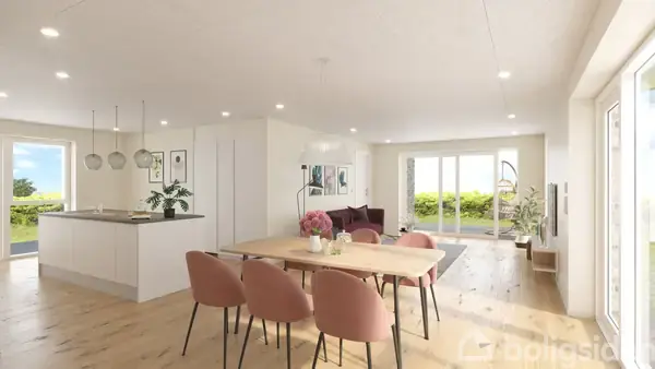 Spisebord med lyserøde stole står i en moderne, lys stue-køkken. Store vinduer åbner mod en frodig have, mens en sofa og planter skaber en hyggelig atmosfære.