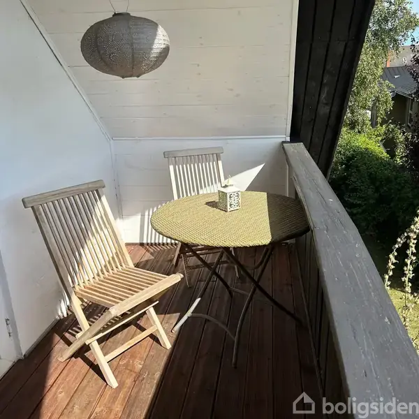Køkken med hvidt skabsarrangement, opvaskemaskine og vask ved vindue. Blå dør til højre, kaffemaskine og brødrister på bordplade. Lys hænger ned fra loftet.