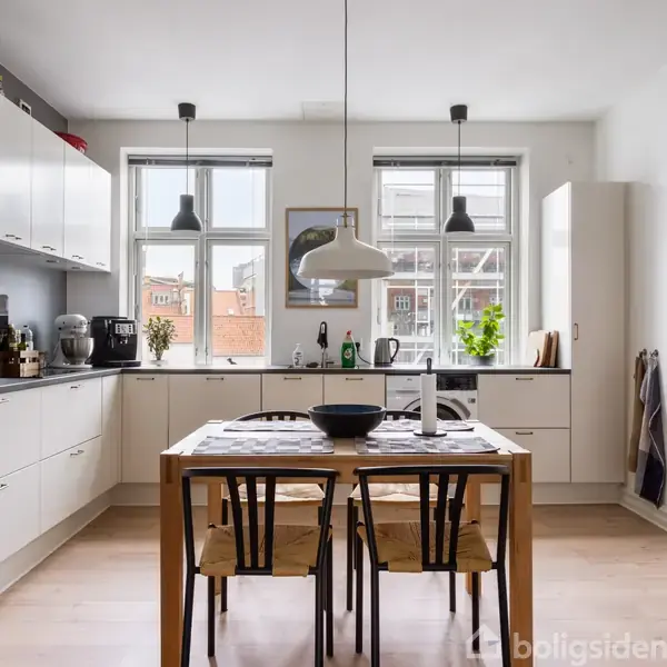 Et moderne køkken med hvide skabe og sorte apparater. Et træbord med fire stole står centralt. Store vinduer lukker lys ind, omgivet af dekorationer og planter.