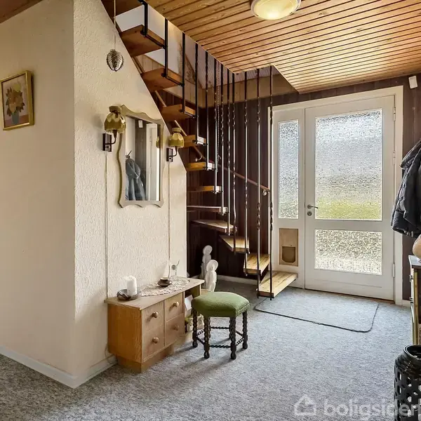 Trappe op ad væg, moderne entré. En dør med glas, et lille skab og en stol ved siden af. Dekorative genstande på vægge og møbler. Lys træloft.
