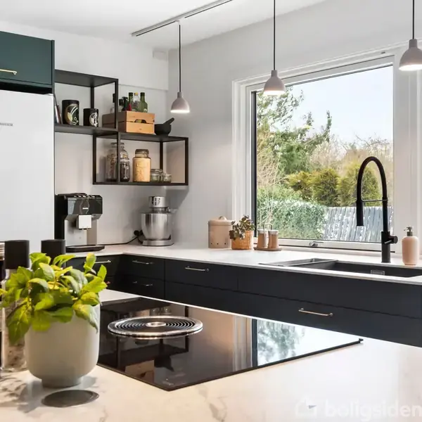 Køkken med sort komfur og hvidevarer i moderne stil. Ved siden af vasken står krydderier og planter. Store vinduer bagved viser en have med træer og hegn.