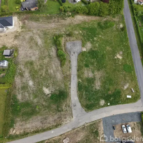 To grunde i et beboelsesområde, en med græs og jordpletter, den anden med en asfalteret sti. Omkranset af huse og en vej til højre.