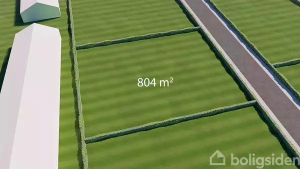 Et markeret jordstykke på 804 m² omgivet af hække ved siden af en lang vej; græsset er jævnt klippet.