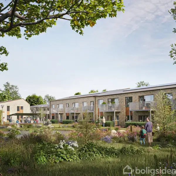 Moderne rækkehuse står roligt i et grønt boligområde. Foran komplekset går en person med et barn på en frodig græsplæne, omgivet af buske og træer, under en klar himmel.