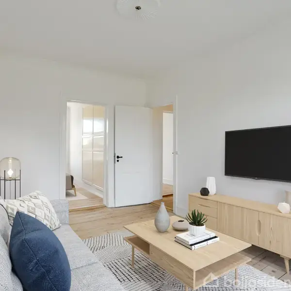 En lys stue med en grå sofa til venstre, et træbord med dekorative genstande i midten, og et fjernsyn på en lav skænk til højre. Døren leder til et andet rum.