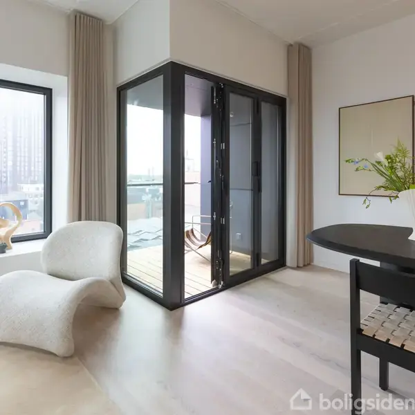 Stol med elegant, buet design står ved siden af et stort vindue. En dør fører ud til en balkon. I rummet er der også et rundt bord med en vase.