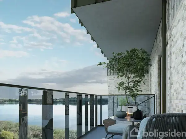 En moderne balkon med glasgelænder, indeholder stole og planter, placeres udendørs med udsigt over en sø og omgivet af skyer på blå himmel.