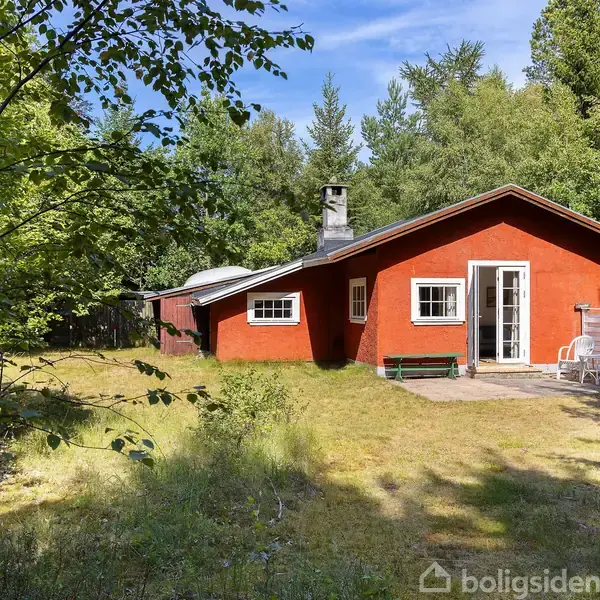 Et rødt hus med skorsten står i en solrig have omgivet af træer. En hvid dør og vinduer er synlige, og en bænk står ved indgangen.
