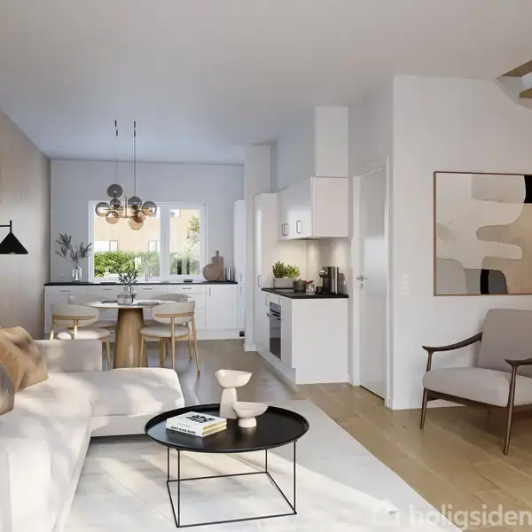 Stue med sofa og sofabord, indrettet i moderne stil. Ved siden af er en spiseplads med bord og stole under en lysekrone. Køkkenet ses i baggrunden ved trappen.