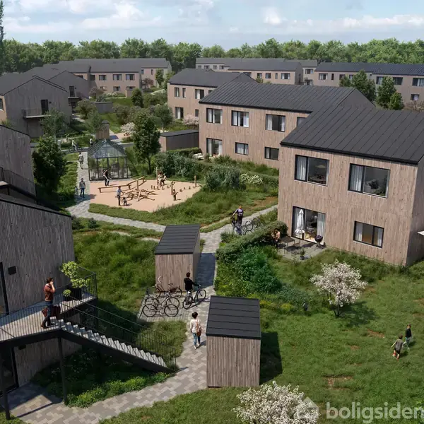 Flere træbeklædte boliger omkranser en grøn park med stier og en legeplads. Mennesker ses gående og cyklende, mens andre sidder udenfor huse i haveområder.
